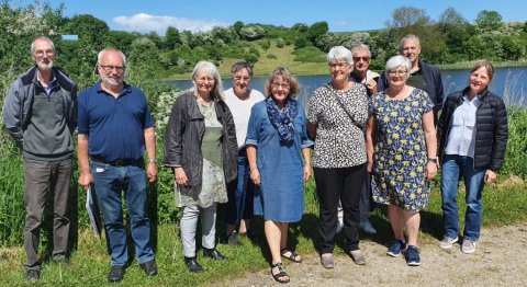 Ved Mjels sø, 22. maj 2022. Fra venstre: Arne H Blom, Claus-Jørn Hjelm, Tamira Mariann Jørgensen, Karin Eriksen, Marianne Nehm, Karin Jensen, Arne Hvid, oldermand Herdis Thomsen Maaløe, Kurt Dreyer og Charlotte Jervelund.